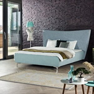 Gestoffeerd bed Londen in blauwe stof met groot hoofdbord en metalen poten, opgemaakt met beddengoed